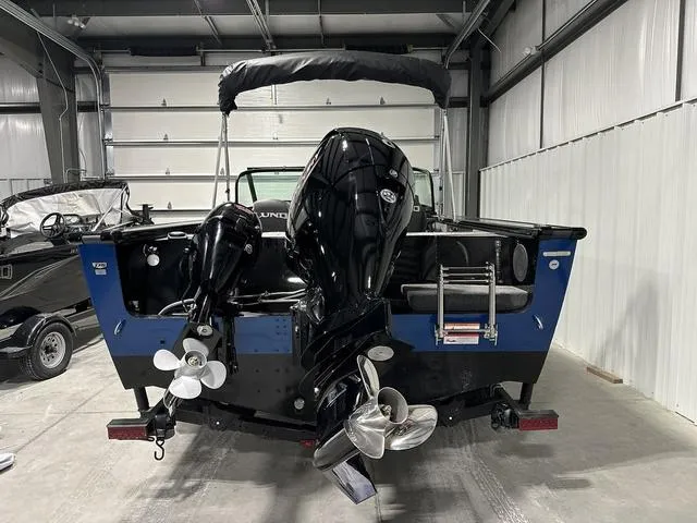 Slide: The Image of 2025 Lund 1875 Fisherman Sport boat in garage, showcasing dual outboard motors. - 4