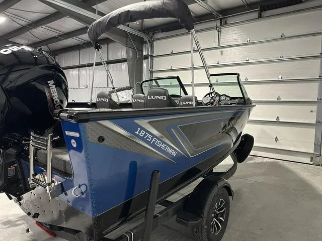 Slide: The Image of 2025 Lund 1875 Fisherman Sport boat in a garage, featuring a sleek blue design. - 6