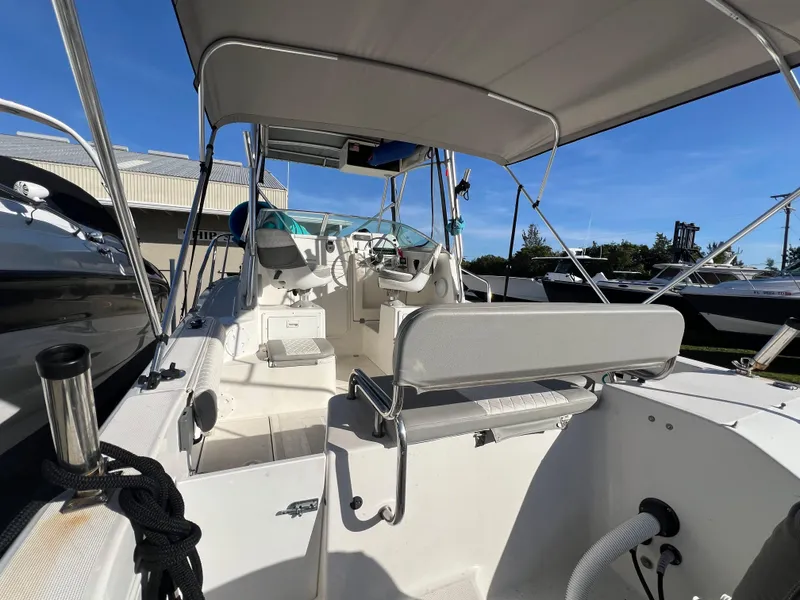Slide: The Image of 2000 Robalo 2440 Walkaround boat interior with seating and helm, docked outdoors. - 10