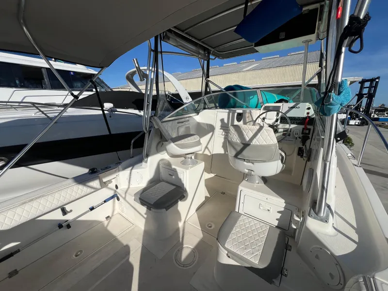 Slide: The Image of 2000 Robalo 2440 Walkaround boat interior with seating and helm, docked under sunny skies. - 15