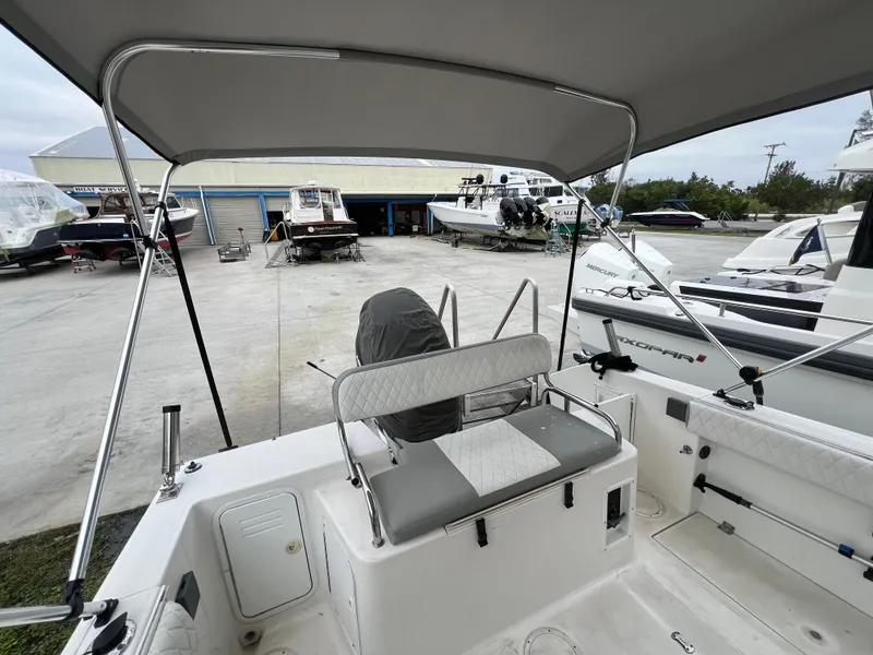Slide: The Image of 2000 Robalo 2440 Walkaround boat interior with seating and canopy in a marina. - 19