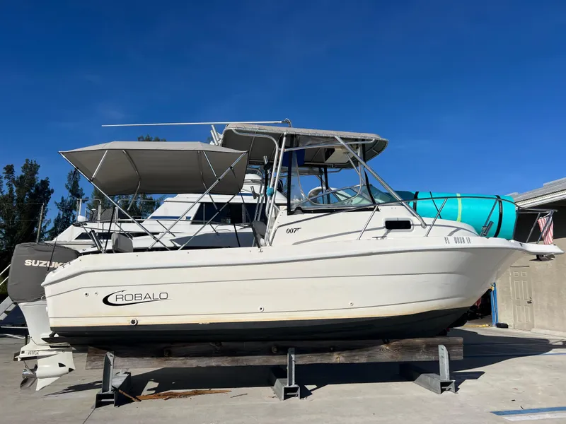 Slide: The Image of 2000 Robalo 2440 Walkaround boat on dry dock with Suzuki outboard motor. - 2
