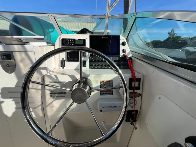 Slide: The Image of Steering wheel and controls of a 2000 Robalo 2440 Walkaround boat. - 21