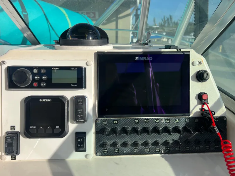 Slide: The Image of Robalo 2440 Walkaround 2000 boat dashboard with Simrad display and Suzuki controls. - 22