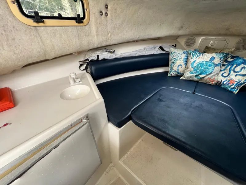 Slide: The Image of Cozy cabin interior of 2000 Robalo 2440 Walkaround with blue seating and nautical-themed pillows. - 28