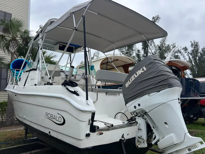 Slide: The Image of 2000 Robalo 2440 Walkaround boat with Suzuki outboard motor, parked outdoors. - 3