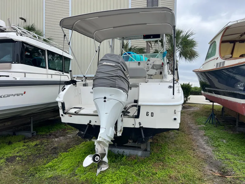 Slide: The Image of 2000 Robalo 2440 Walkaround boat with covered outboard motor, parked on grass. - 4