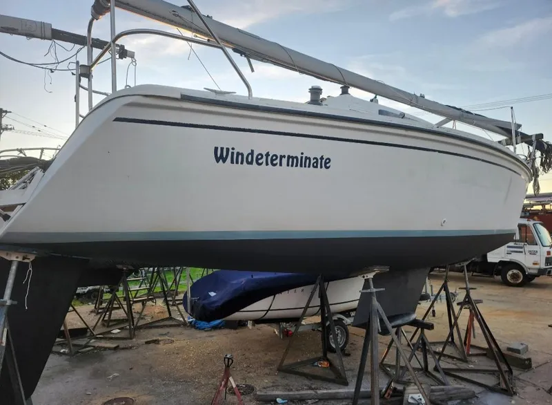 The Image of 1987 Hunter 26.5 sailboat named "Windeterminate" on stands in a boatyard. - 0