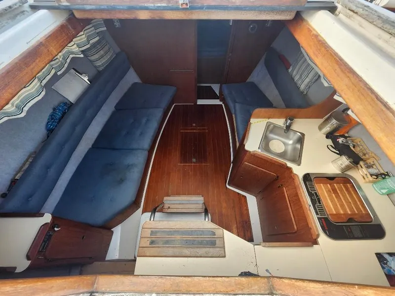 Slide: The Image of Interior of a 1987 Hunter 26.5 sailboat, featuring cozy seating and compact kitchen area. - 1