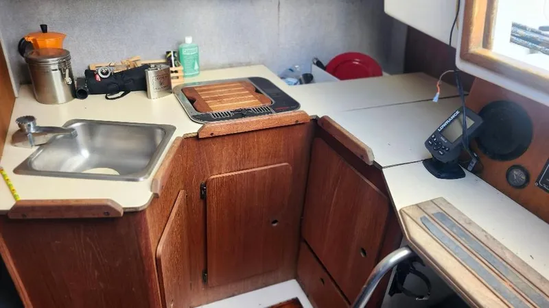 Slide: The Image of 1987 Hunter 26.5 sailboat interior kitchen with sink, stove, and navigation equipment. - 10