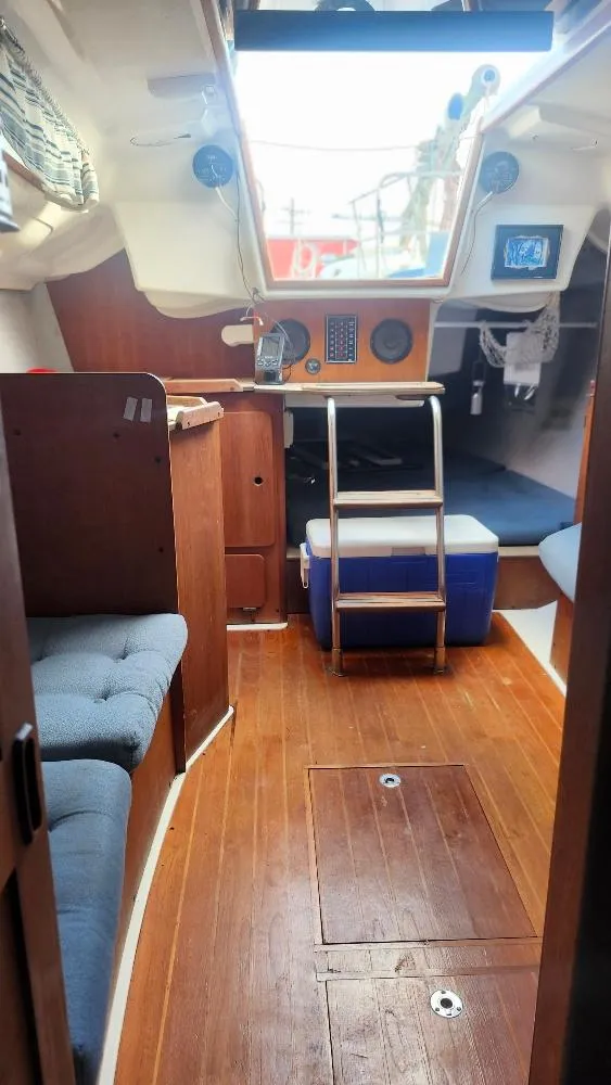 Slide: The Image of Interior of a 1987 Hunter 26.5 sailboat with wooden flooring and seating area. - 19