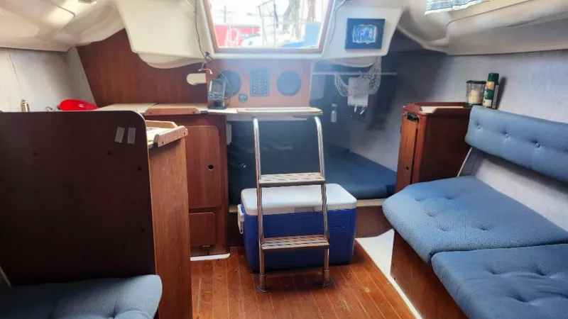 Slide: The Image of Interior of a 1987 Hunter 26.5 sailboat with wooden furnishings and blue seating. - 2