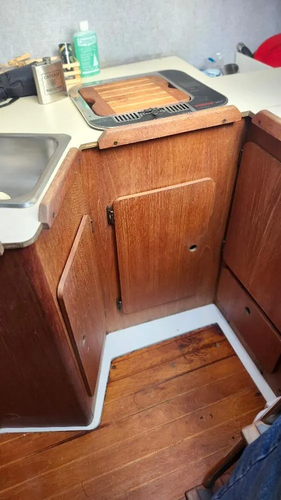 Slide: The Image of 1987 Hunter 26.5 boat interior with wooden cabinetry and compact kitchen area. - 21