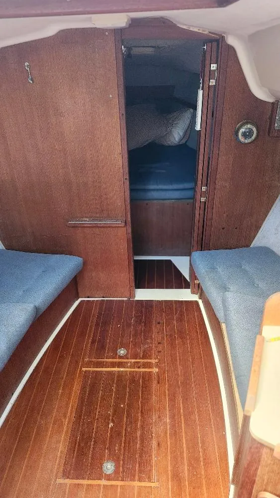 Slide: The Image of Interior of 1987 Hunter 26.5 sailboat with wooden flooring and blue seating. - 4