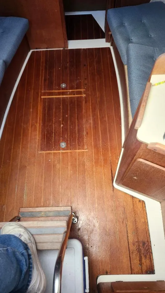 Slide: The Image of Interior of 1987 Hunter 26.5 sailboat with wooden flooring and blue seating. - 6