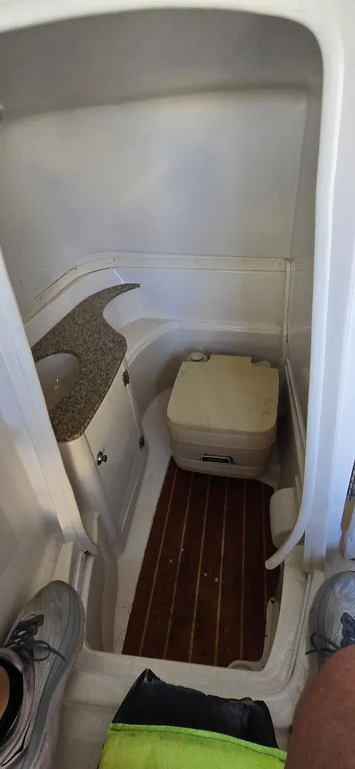 Slide: The Image of 2010 Monterey 254FS boat interior with compact bathroom and wooden flooring. - 15