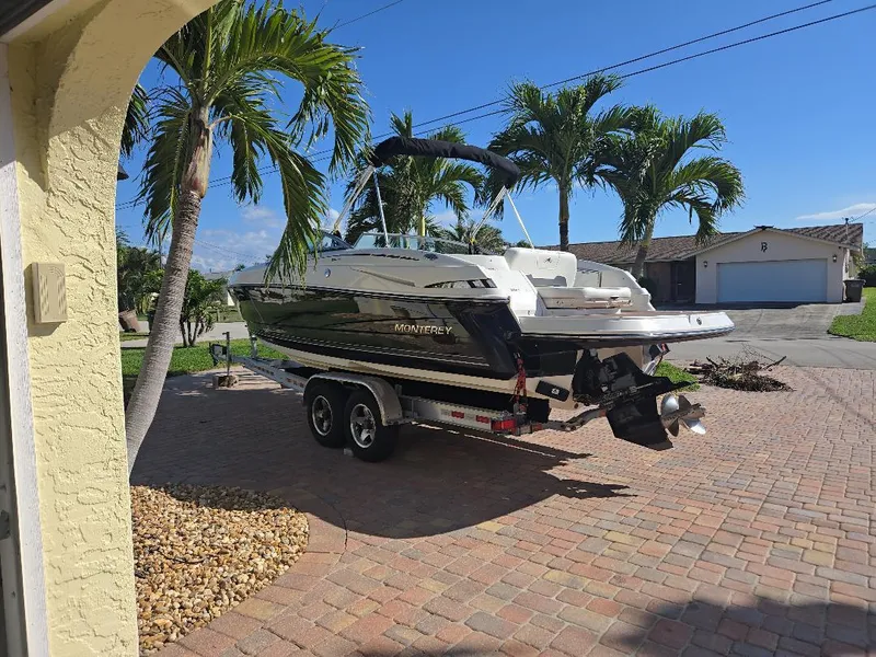 Slide: The Image of 2010 Monterey 254FS boat on trailer in sunny driveway with palm trees. - 2