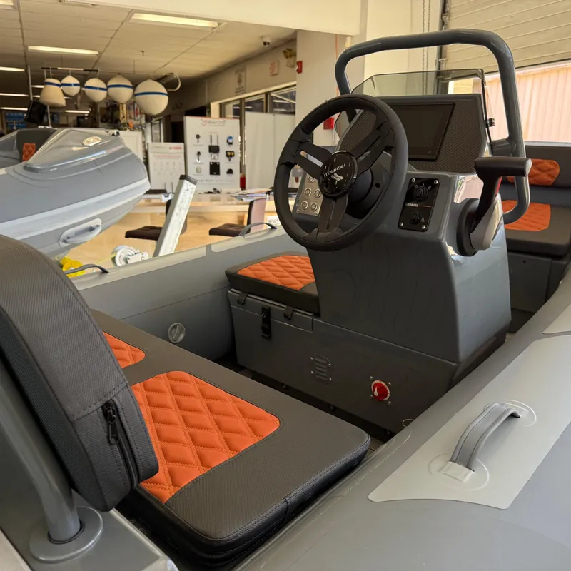 Slide: The Image of 2025 Highfield Sport 360 boat interior with orange and gray seating, steering console, and modern design. - 5