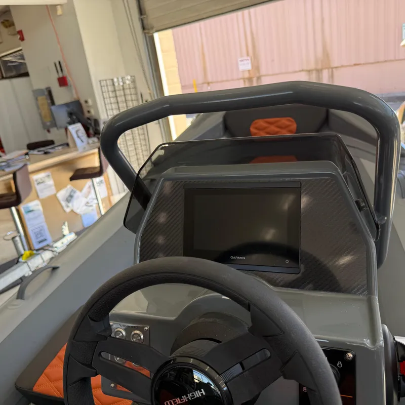 Slide: The Image of 2025 Highfield Sport 360 boat dashboard with steering wheel and display screen in a showroom. - 8
