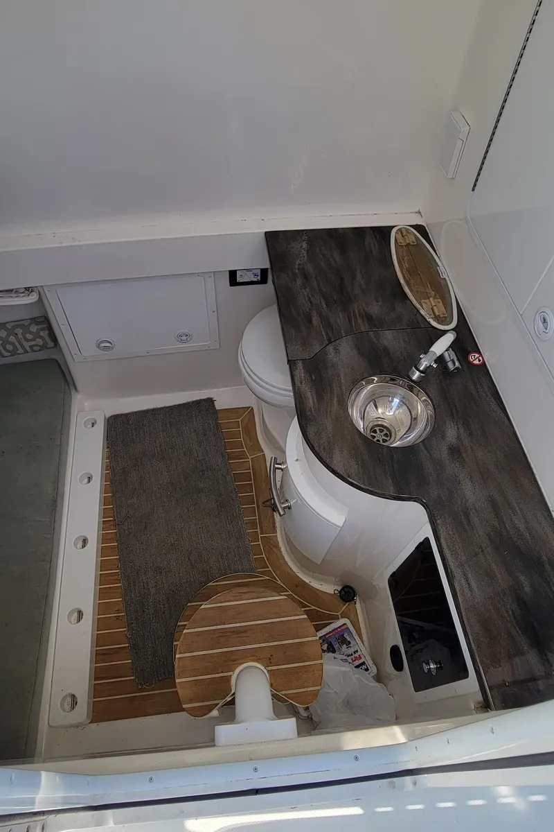 Slide: The Image of 2018 Regulator 34SS boat bathroom with sink, toilet, and wooden flooring. - 12