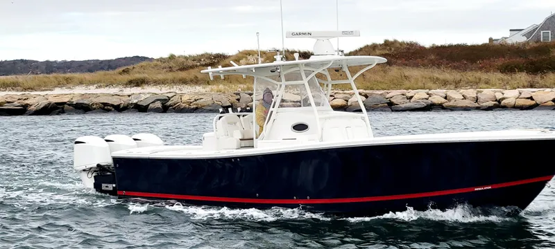 Slide: The Image of 2018 Regulator 34SS boat cruising near rocky shoreline. - 2