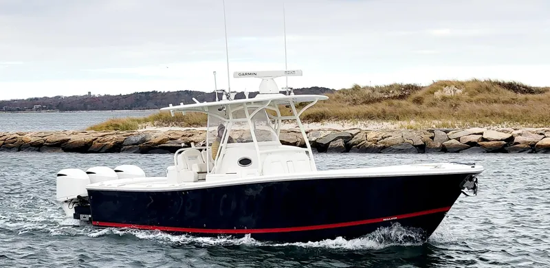 Slide: The Image of 2018 Regulator 34SS boat cruising on water near rocky shoreline. - 4