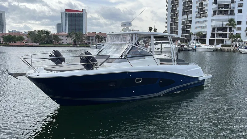 Slide: The Image of 2019 Jeanneau Leader 10.5 boat on water, with modern buildings in the background. - 11