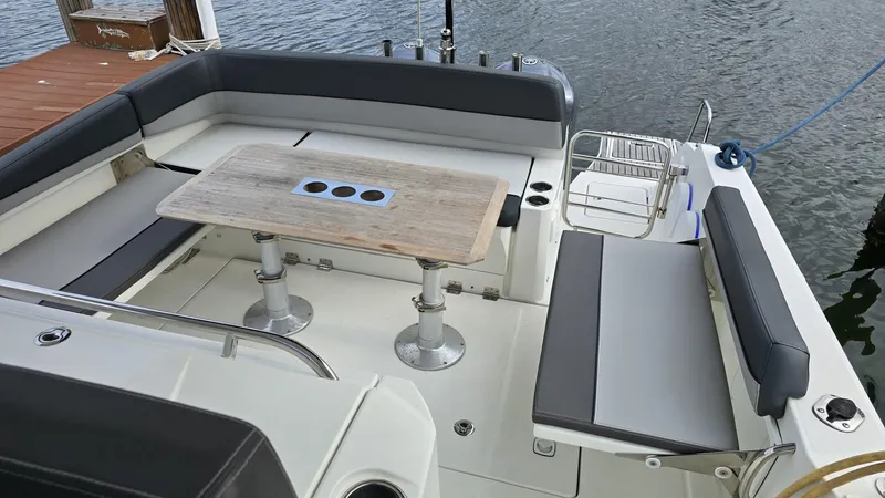 Slide: The Image of 2019 Jeanneau Leader 10.5 boat interior with seating and table, docked by the water. - 4