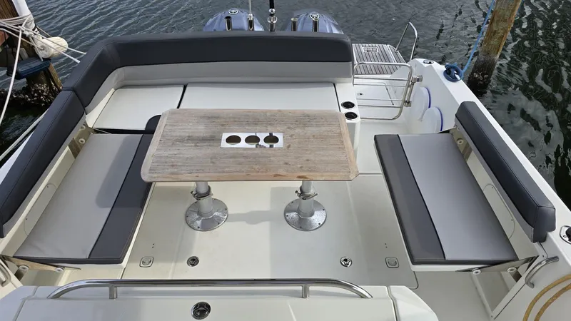 Slide: The Image of 2019 Jeanneau Leader 10.5 boat deck with seating and table, docked by water. - 5