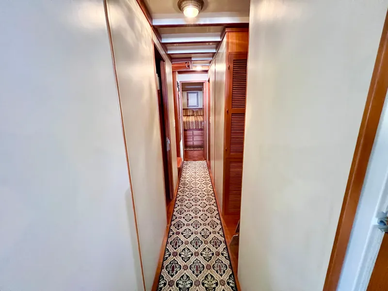 Slide: The Image of Narrow hallway inside 2001 Kadey-Krogen 48 Whaleback yacht with patterned carpet and wooden accents. - 16