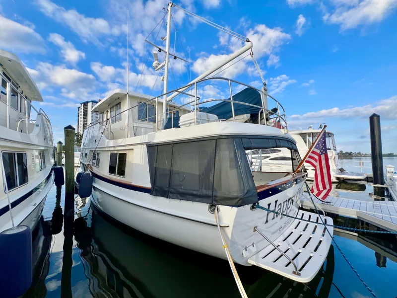 Slide: The Image of 2001 Kadey-Krogen 48 Whaleback yacht docked, featuring American flag and clear blue sky. - 2