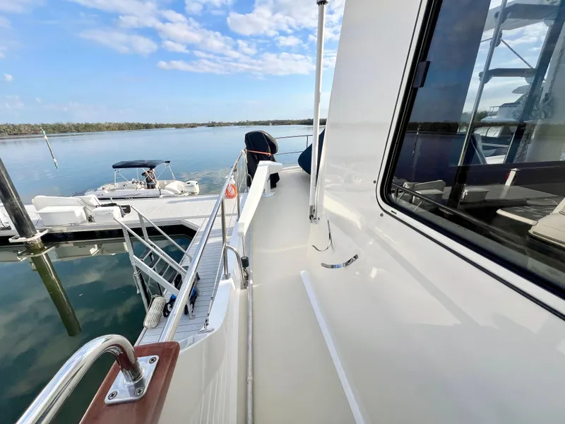 Slide: The Image of 2001 Kadey-Krogen 48 Whaleback yacht docked, showcasing sleek deck and serene water view. - 49