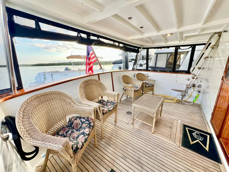Slide: The Image of 2001 Kadey-Krogen 48 Whaleback yacht deck with wicker chairs and American flag. - 6