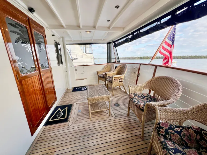 Slide: The Image of 2001 Kadey-Krogen 48 Whaleback yacht deck with wicker chairs and American flag. - 7