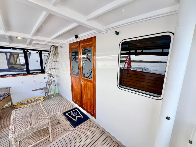 Slide: The Image of 2001 Kadey-Krogen 48 Whaleback yacht deck with wooden doors and seating area. - 8