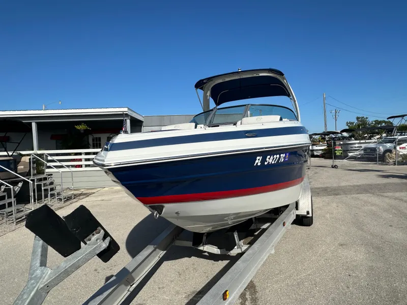Slide: The Image of 2022 Crownline 260 XSS boat on trailer, blue and white exterior, sunny day. - 3