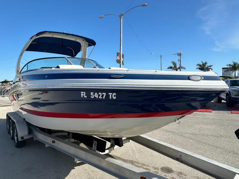 Slide: The Image of 2022 Crownline 260 XSS boat on trailer, blue and white design, sunny day. - 4
