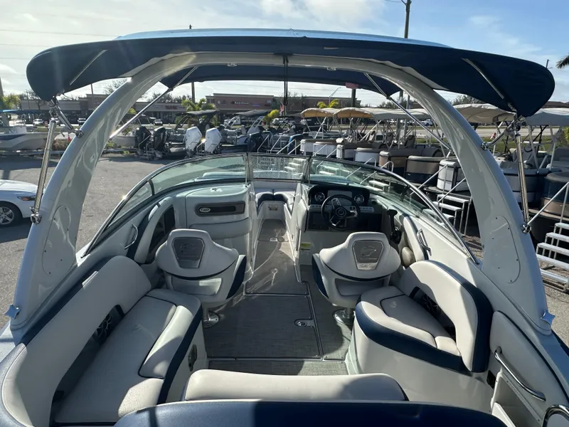 Slide: The Image of 2022 Crownline 260 XSS boat interior with seating and helm, parked in marina. - 9