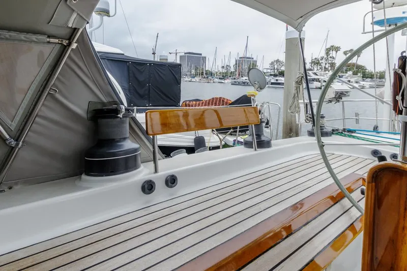 Slide: The Image of Deck view of 1994 Farr 55 yacht in marina, featuring wooden seating and nautical equipment. - 18