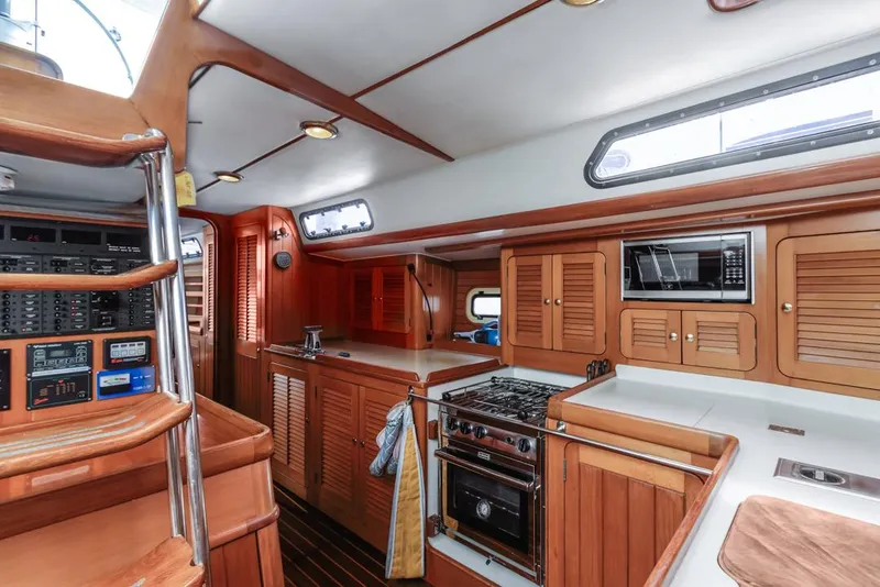 Slide: The Image of Interior of a 1994 Farr 55 yacht with wooden cabinetry and modern kitchen appliances. - 45