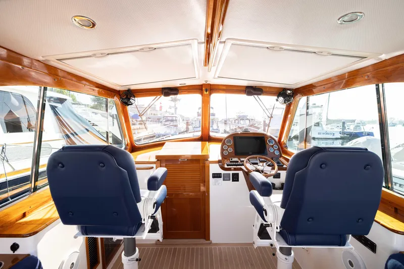 Slide: The Image of Interior of 2016 Hinckley 37 Picnic Boat with dual navy seats and wooden accents. - 16