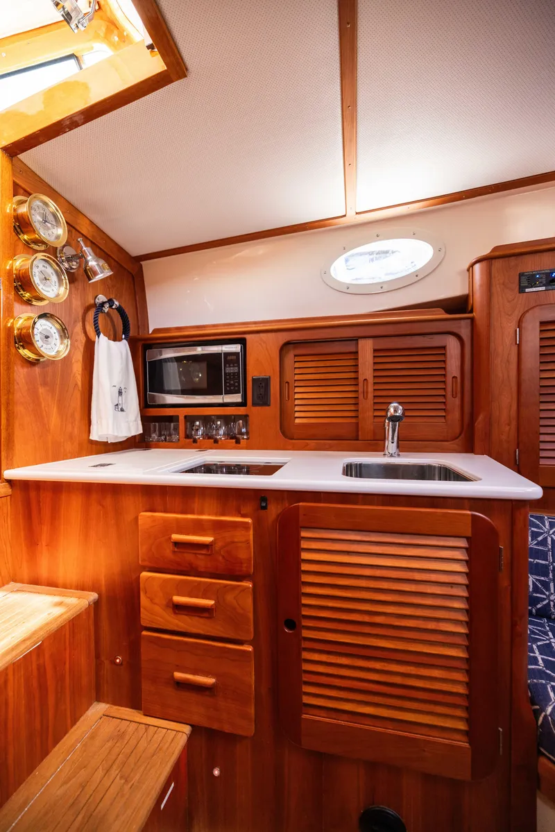 Slide: The Image of 2016 Hinckley 37 Picnic Boat interior with wooden cabinetry and modern kitchen amenities. - 26