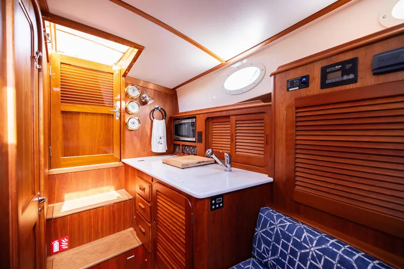Slide: The Image of Interior of 2016 Hinckley 37 Picnic Boat with wooden cabinetry and compact kitchen area. - 28