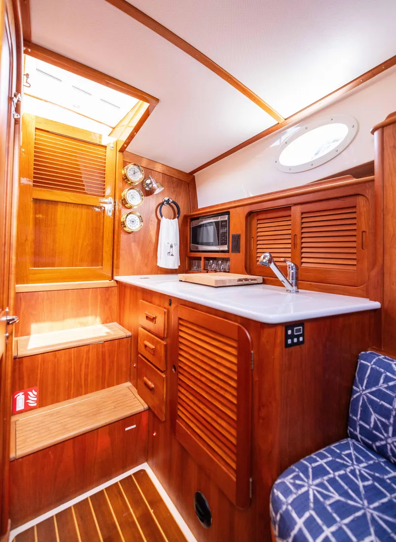 Slide: The Image of Interior of 2016 Hinckley 37 Picnic Boat with wooden cabinetry and compact kitchen area. - 29