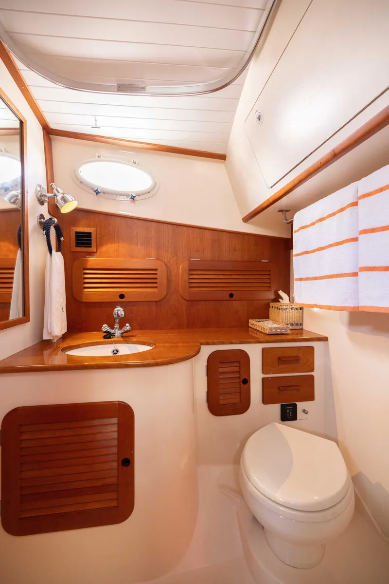 Slide: The Image of 2016 Hinckley 37 Picnic Boat bathroom with wooden accents and modern fixtures. - 33