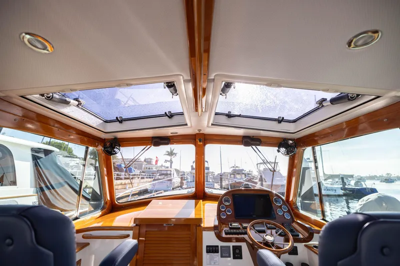 Slide: The Image of Interior view of 2016 Hinckley 37 Picnic Boat with wooden accents and marina backdrop. - 35