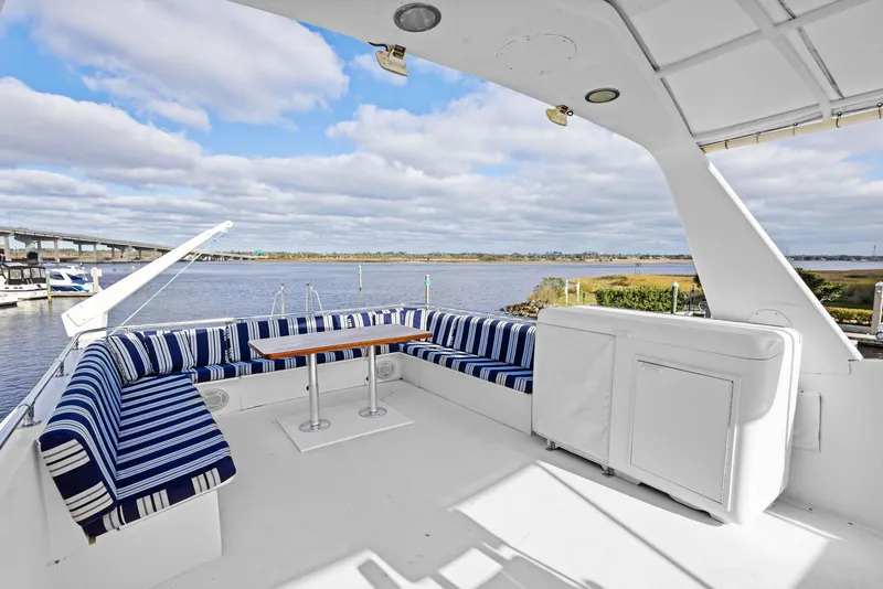 Slide: The Image of 1987 Hatteras 68 Cockpit Motor Yacht with spacious deck and striped seating by the water. - 11