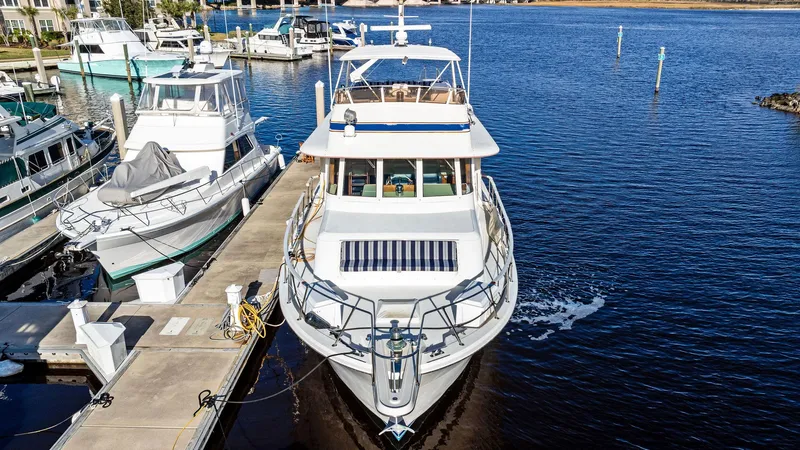 Slide: The Image of 1987 Hatteras 68 Cockpit Motor Yacht docked at marina, front view. - 2