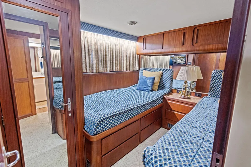 Slide: The Image of Interior of 1987 Hatteras 68 Cockpit Motor Yacht with twin beds and wooden cabinetry. - 28