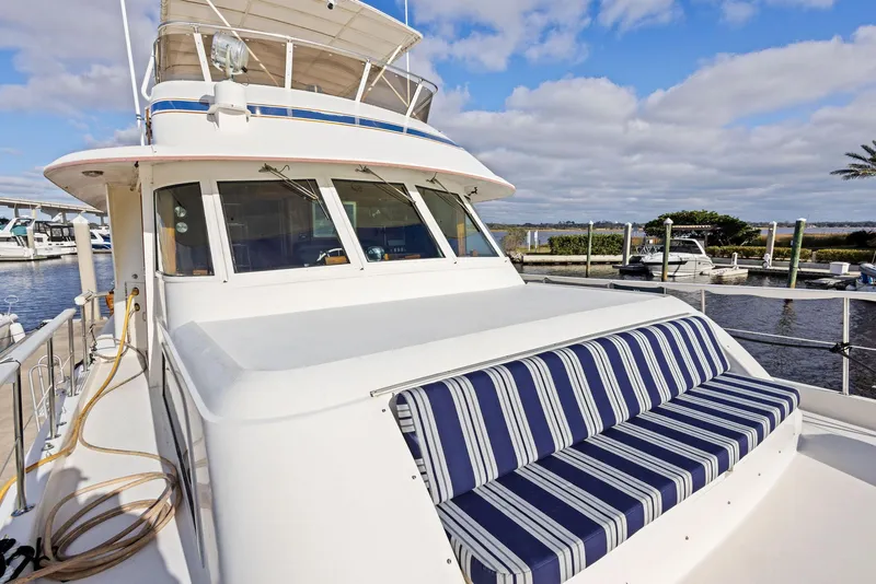 Slide: The Image of 1987 Hatteras 68 Cockpit Motor Yacht with striped seating, docked under a blue sky. - 8